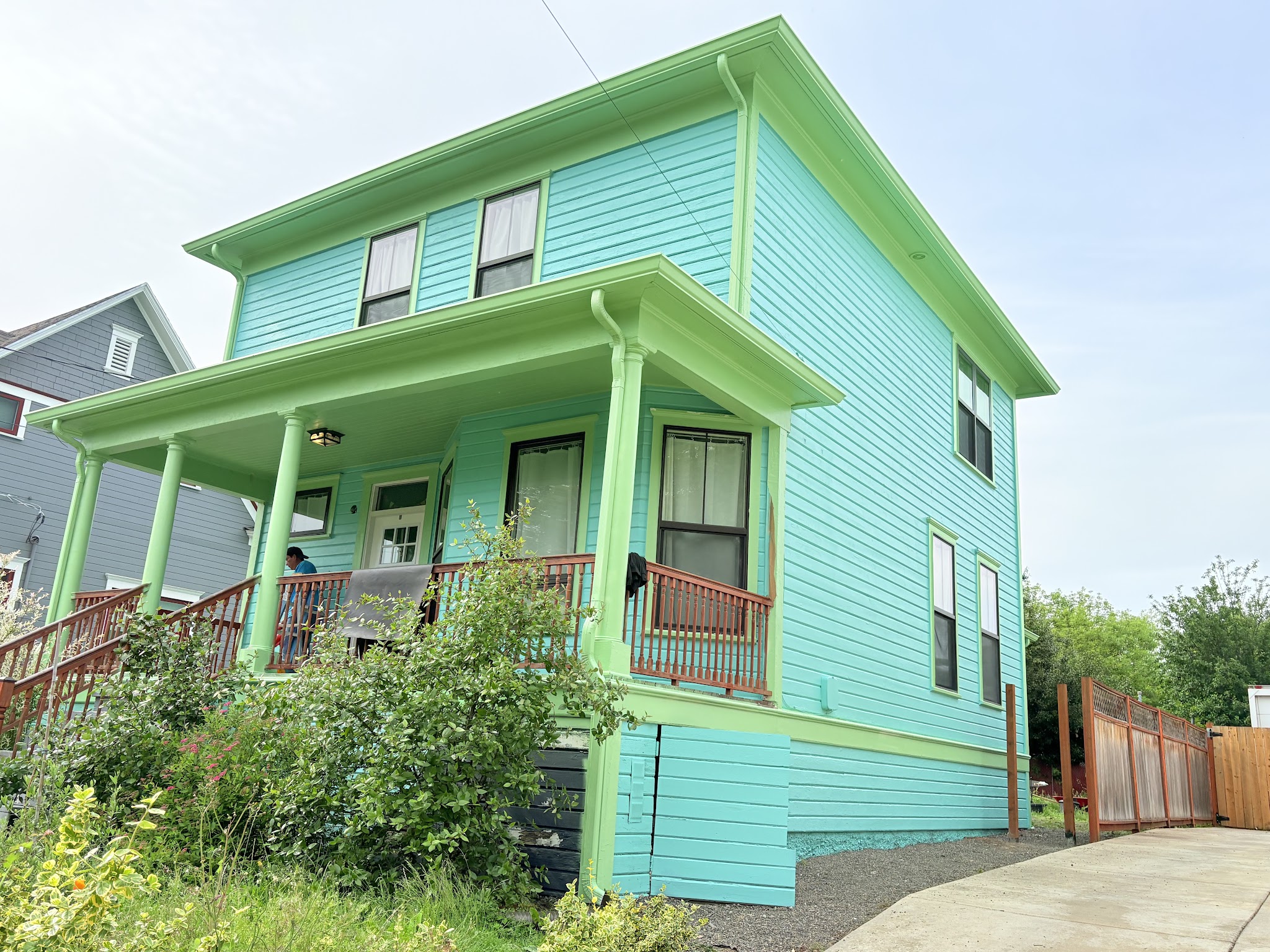 Freshly repainted two-story home in bold teal with lime green trim